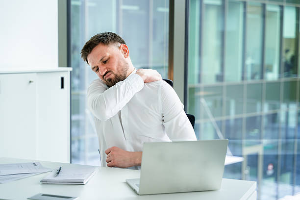 istock Businessman Experiencing Shoulder Pain While Working at Office Desk 2204692407