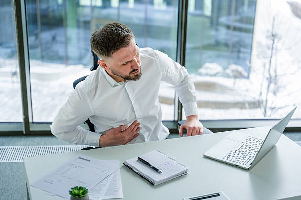 istock Businessman in Office Experiencing Chest Pain While Using Laptop at Desk 2204693804