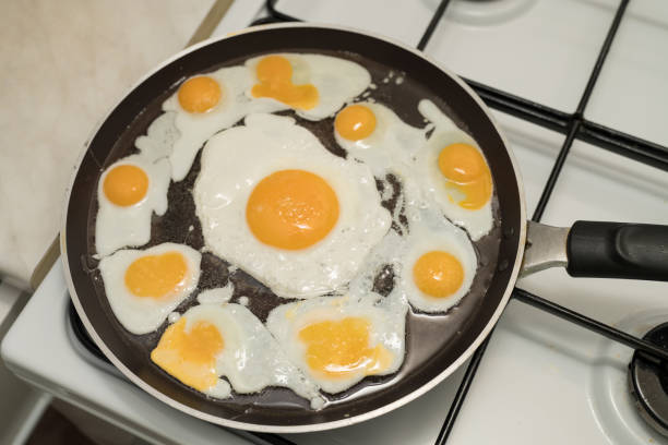 istock Chicken egg and 9 quail eggs in frying pan. 2204696663