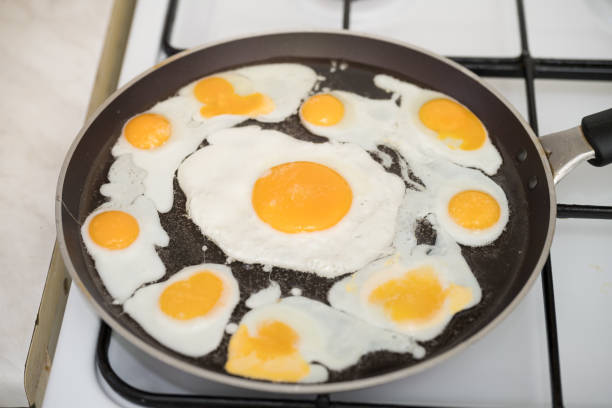 istock Chicken egg and 9 quail eggs in frying pan. 2204696697