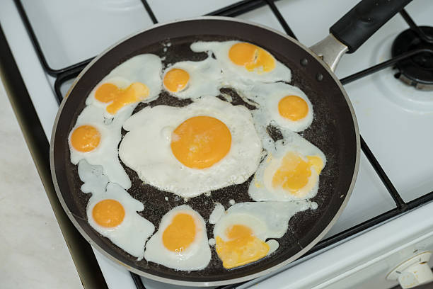 istock Chicken egg and 9 quail eggs in frying pan. 2204696982