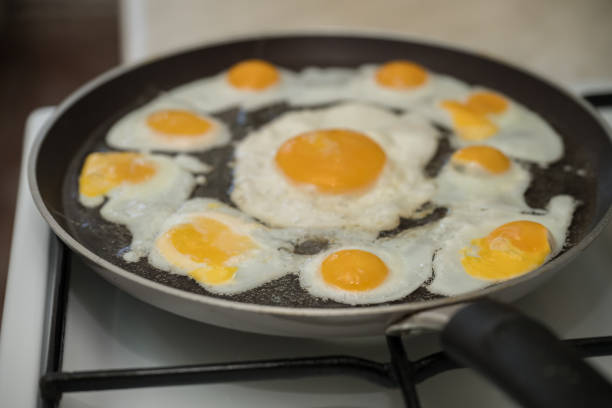 istock Chicken egg and 9 quail eggs in frying pan. 2204697035