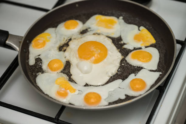 istock Chicken egg and 9 quail eggs in frying pan. 2204697164