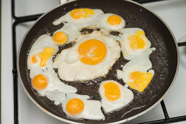 istock Chicken egg and 9 quail eggs in frying pan. 2204697327