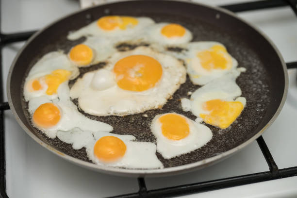 istock Chicken egg and 9 quail eggs in frying pan. 2204697343