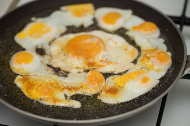 istock Chicken egg and 9 quail eggs in frying pan. 2204697372