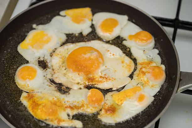 istock Chicken egg and 9 quail eggs in frying pan. 2204697399