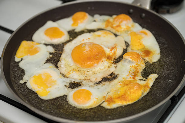 istock Chicken egg and 9 quail eggs in frying pan. 2204697402