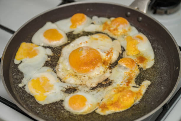 istock Chicken egg and 9 quail eggs in frying pan. 2204697442