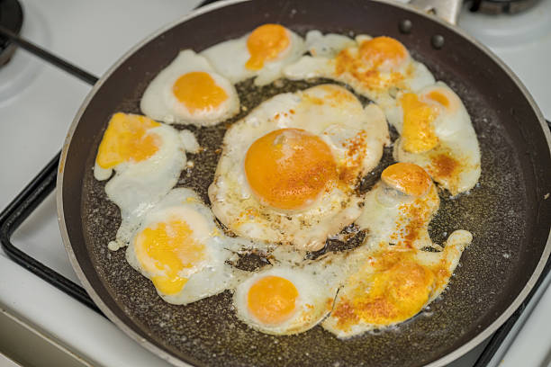 istock Chicken egg and 9 quail eggs in frying pan. 2204697561