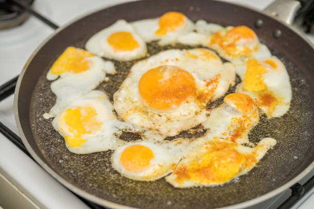 istock Chicken egg and 9 quail eggs in frying pan. 2204697577