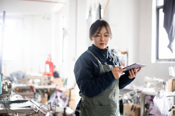 istock Asian female blue-collar workers are using tablets in the sewing workshop. 2204698325