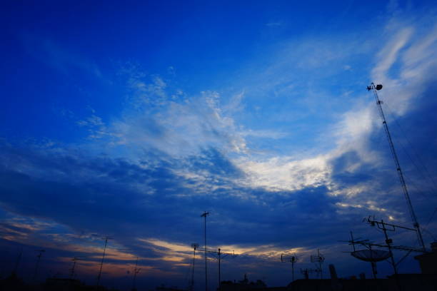 Dramatic sunset sky with clouds and silhouettes. A vibrant blue sky with fluffy white clouds