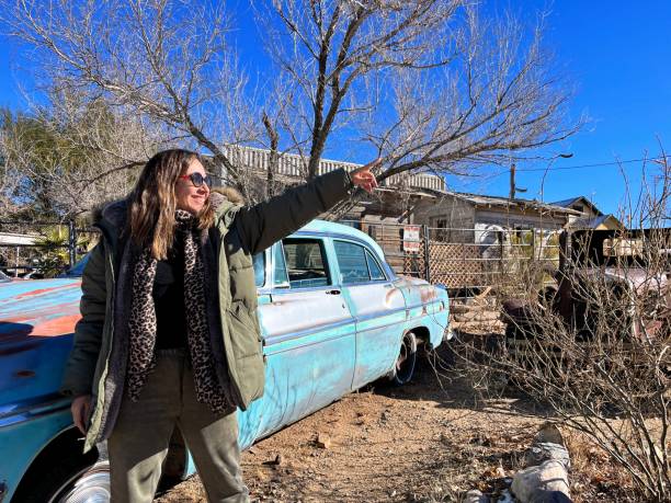 Tourist pointing at a landmark in Hackberry, a ghost town along Route 66 in Arizona, situated beside an old, rusty car, capturing the essence of Americana and exploration