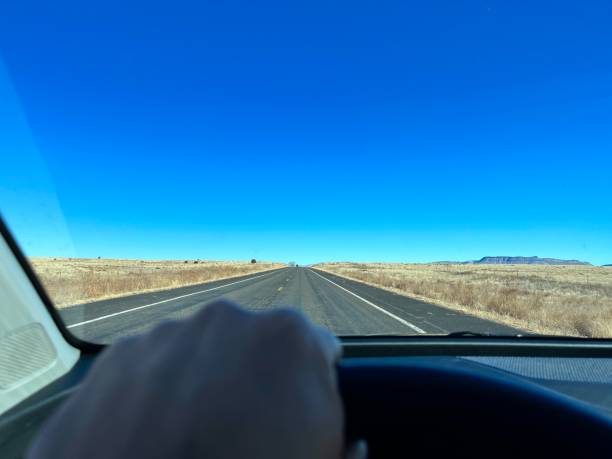 Hand gripping the steering wheel while driving along the historic Route 66 highway, surrounded by the stunning Arizona desert landscape under a vibrant blue sky
