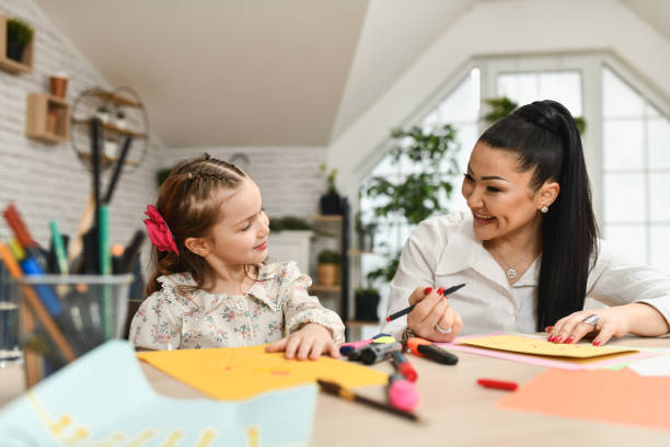 istock Mom and Daughter Bonding Over Fun Drawing Session on Bright Papers 2204704363