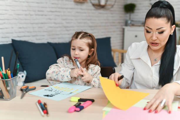 istock Mother and Daughter Looking Focused While Designing Greeting Cards on Colorful Sheets 2204704942