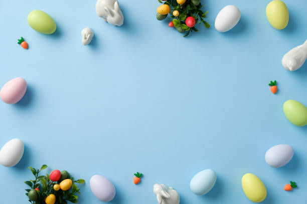istock Easter holiday greeting card template. Flat lay pastel Easter eggs and white rabbits on blue background 2204705171