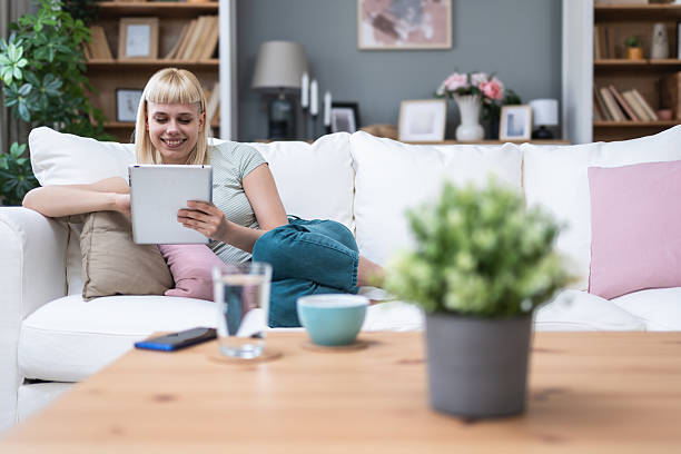 istock Attractive woman freelancer worker using digital tablet sitting at cozy sofa in living room. Successful businesswoman text message in home. Online technology concept, remote job e-commerce e-learning. 2204705219