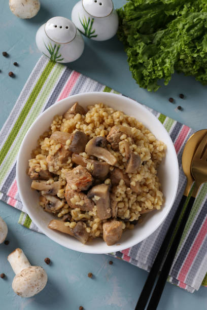 istock Pork with bulgur and champignons served in white bowl on blue table 2204706365