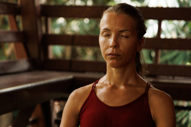 Woman meditating with closed eyes and a serene expression on wooden bench