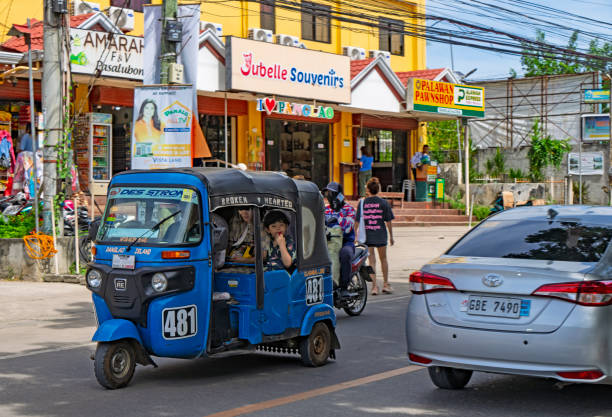 Alona Beach, Main Street, Philippines, January 2025:  Traffic including, cars, tuk tuks and motorcycles on the main road through Alona Beach.