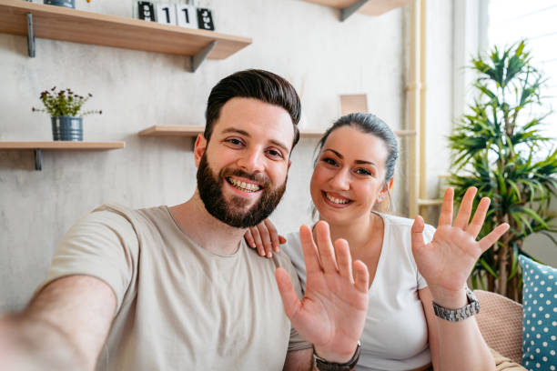 istock Young Couple Having A Video Call While Sitting On The Sofa At Home 2204709937