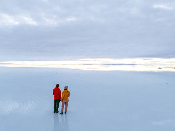 istock Couple Standing on Vast Salt Flats Under Cloudy Sky 2204710475