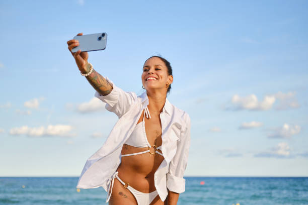istock Young woman taking a selfie on the beach 2204710882