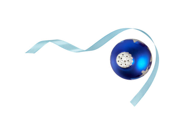 Closeup of hanging Christmas ornament. Christmas tree, lights, and presents in background. Copy space.