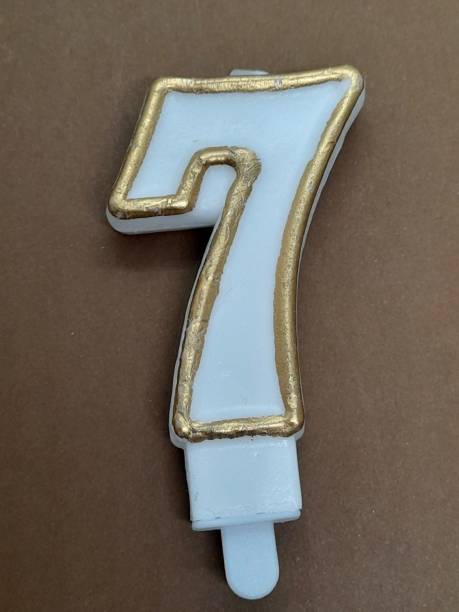 istock Number 7 birthday candle with brown background 2204718007