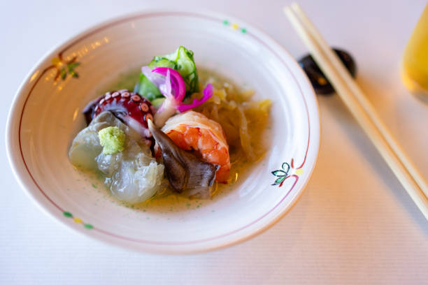 istock Traditional Japanese appetizer with fresh shrimp, octopus, mollusks, and fermented vegetables, served on a ceramic plate with wasabi and pickled toppings 2204724696