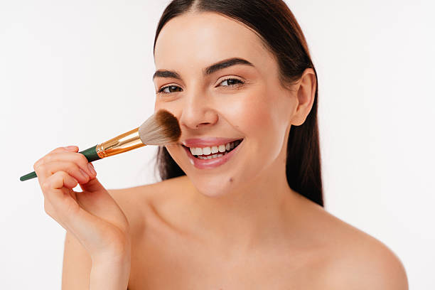 istock Smiling Woman Applying Makeup with Brush on White Background 2204724752