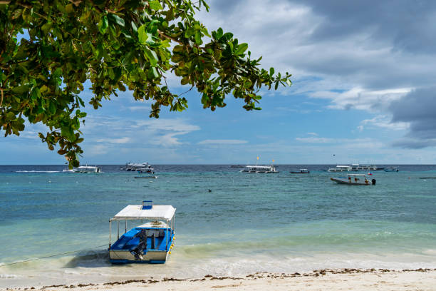 Relaxing hammock in a palm forest.Beautiful landscape on a white sandy beach. Boats on the background of the turquoise sea and the blue sky with clouds. The concept of travel and leisure.