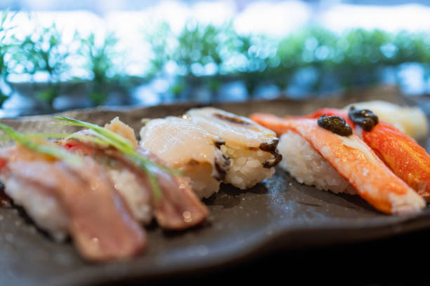 istock Assorted sushi set with flame-seared tuna, fresh scallop, and crab nigiri delicately arranged on a dark ceramic plate, capturing the essence of Japanese fine dining 2204725449