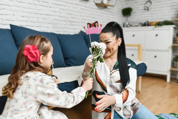 Affectionate Daughter Surprising Mother With Flowers and Paper Crown