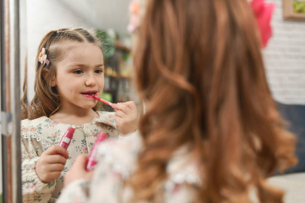 istock Charming Girl Admiring Her Lips in the Mirror After Applying Lip Gloss 2204727980