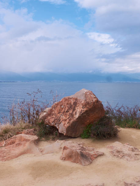 istock Large Red Rock by Erhai Lake with Distant Mountain View 2204732072