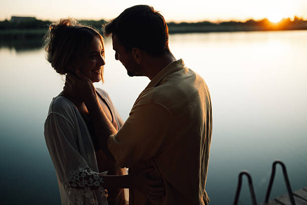 istock Romantic couple embracing by the lake at sunset 2204734607