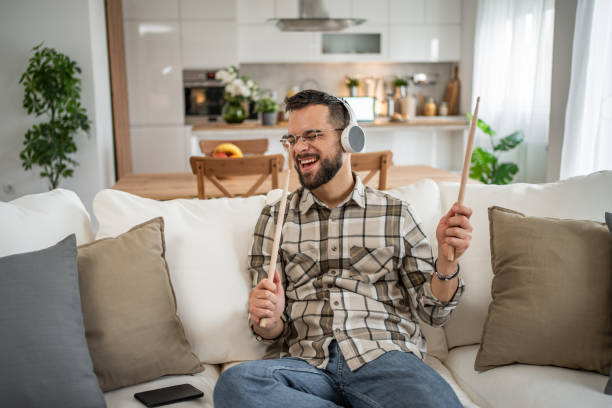 istock Young man playing imaginary drums and singing at home 2204735095
