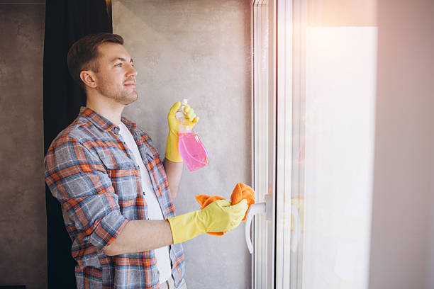 istock Janitor cleaning a window with spray bottle and rag 2204737215