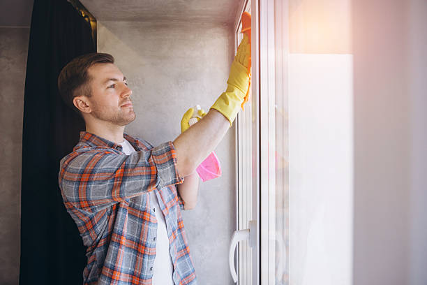 istock Man Cleaning Windows at Home wearing Yellow Gloves 2204737219