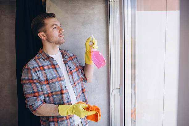 istock Janitor Cleaning Window Glass with Spray Bottle and Orange Cloth 2204737234