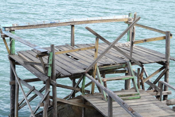 n old wooden hut stands by the shore, weathered by time. The sea breeze and waves slowly break it down, leaving behind memories of a shelter once filled with stories