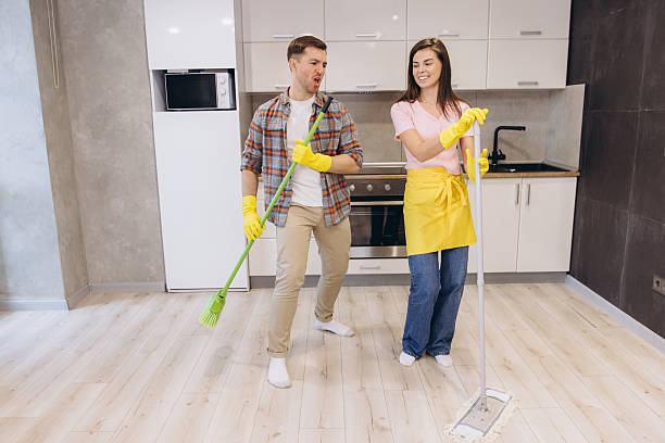 istock Couple having fun cleaning the kitchen floor with broom and mop 2204737657