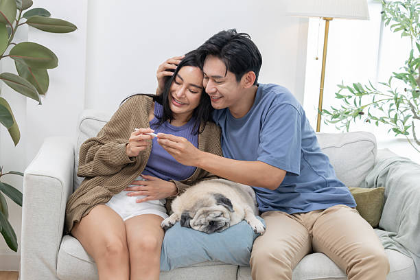 istock Couple celebrates a joyful moment while checking a positive pregnancy test at home with their pug dog 2204738413