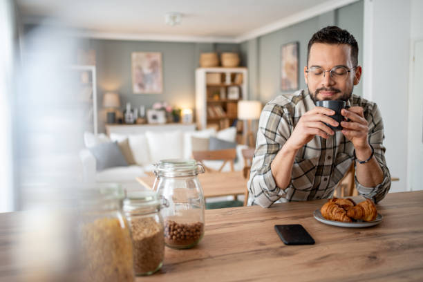 istock Young man enjoying a relaxing breakfast at home 2204740046