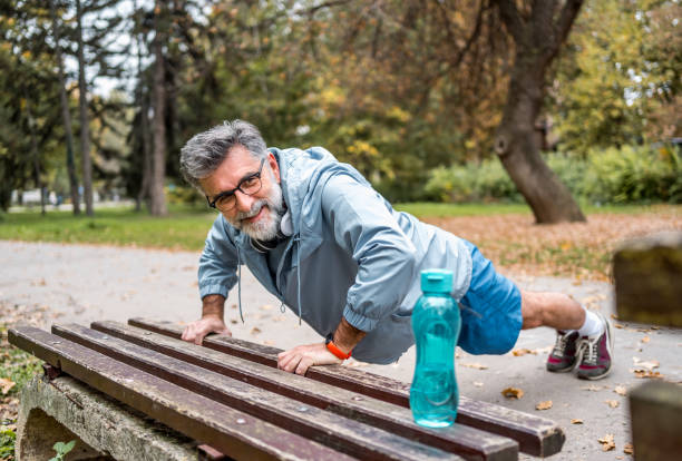 istock Mature man doing push-ups on a bench in the park 2204740520