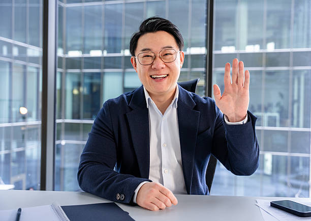istock Professional Businessman Waving and Smiling in Modern Office Workspace 2204747331