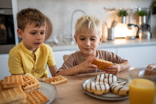 istock Two brothers enjoying delicious waffles and donuts for breakfast 2204747750